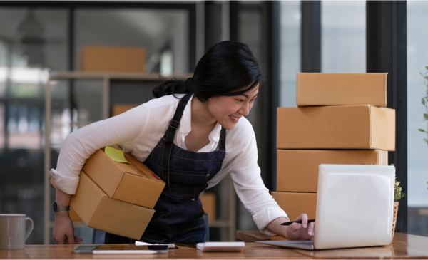 a-woman-holding-a-box-while-using-the-laptop