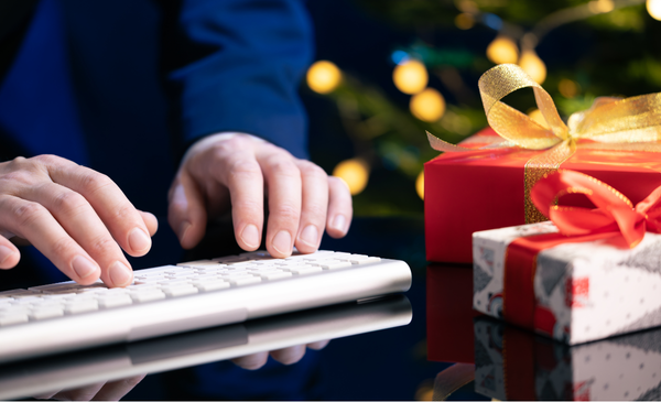 a-hand-typing-with-gifts-beside