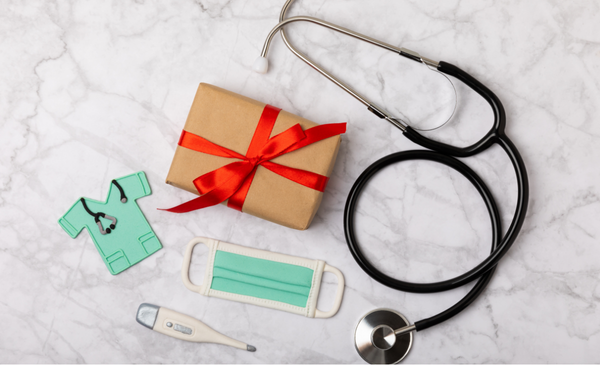 a-brown-gift-box-with-red-ribbon-beside-a-mask-and-stethoscope