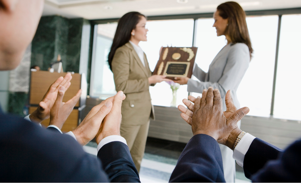 a-woman-handing-an-award-to-an-employee
